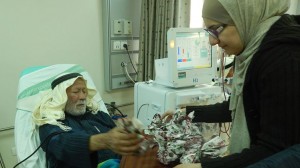 دينا القدومي "منسقة برنامج الدعم النفسي في المستشفيات" تعطي أحد المرضى التفاح