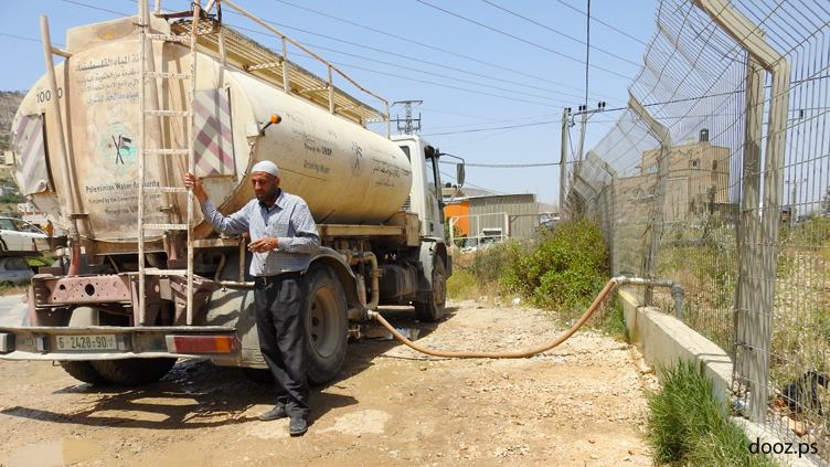موظف البلدية على سيارة المياه سليمان حنني ينتظر أن يمتلئ الصهريج الذي يقوم بتعبئته من بئر ارتوازي روجيب